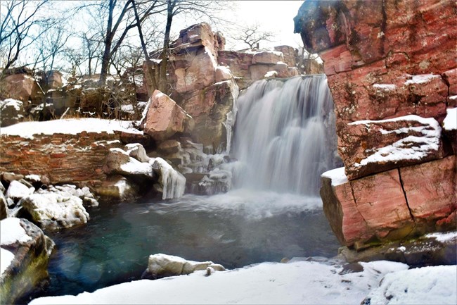 Waterfall surrounded by snow-covered rocks.
