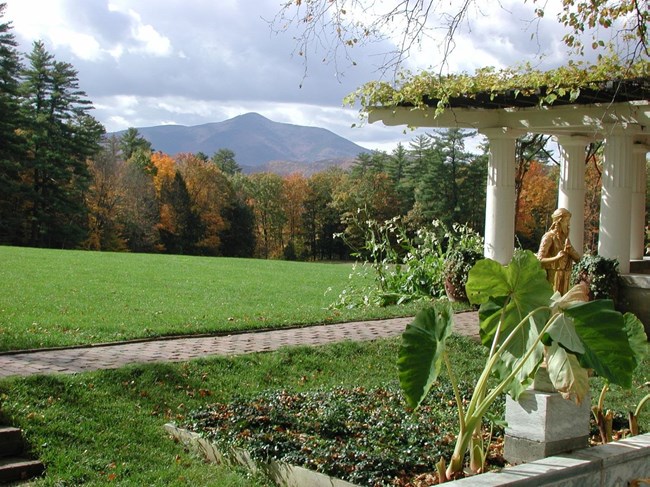 White columns in a garden set against a distant view of a mountain peak in the autumn.