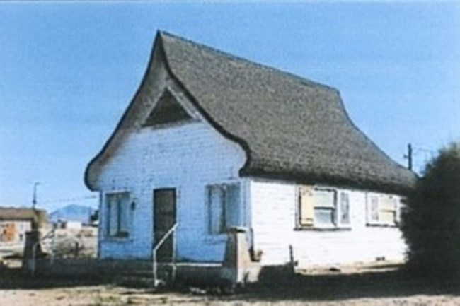 A small, white, one story cottage.