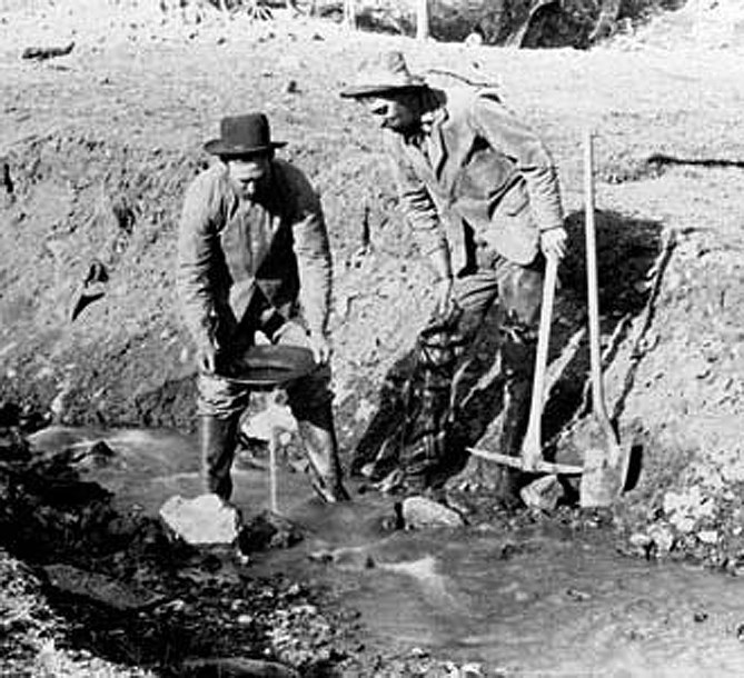 two gold miners in a river bed