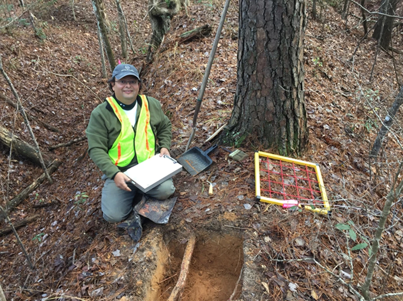 man squatting by tree with archeological dig