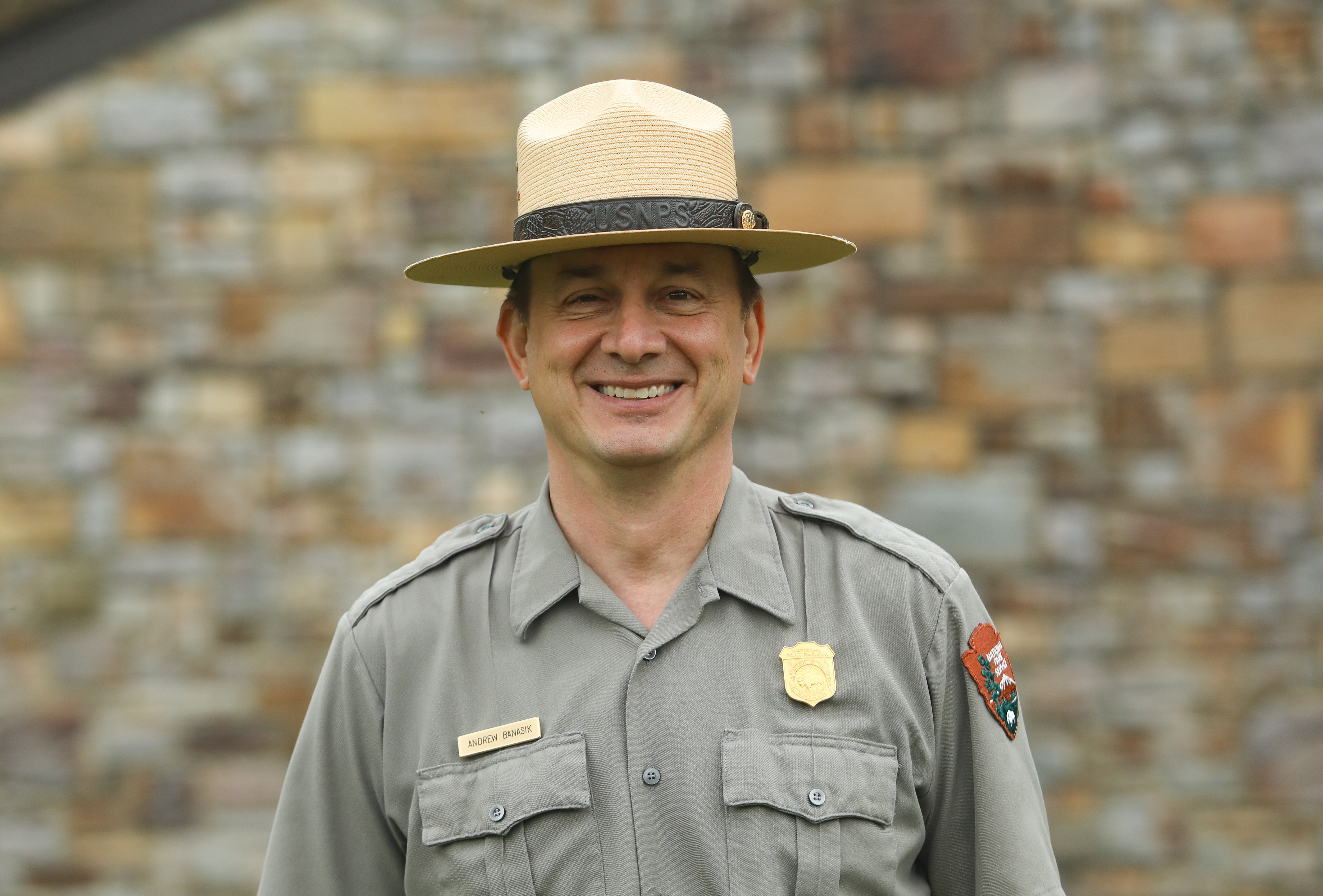 Andrew in his uniform, in front of a brick wall.