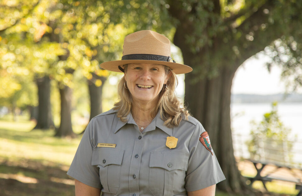 Tammy Stidham A woman in a National Park Service ranger uniform in front of trees.