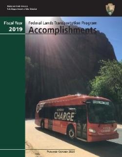 A red zero emissions bus in front of a cliff face