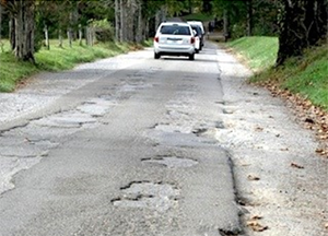 broken pavement with white cars in the distance