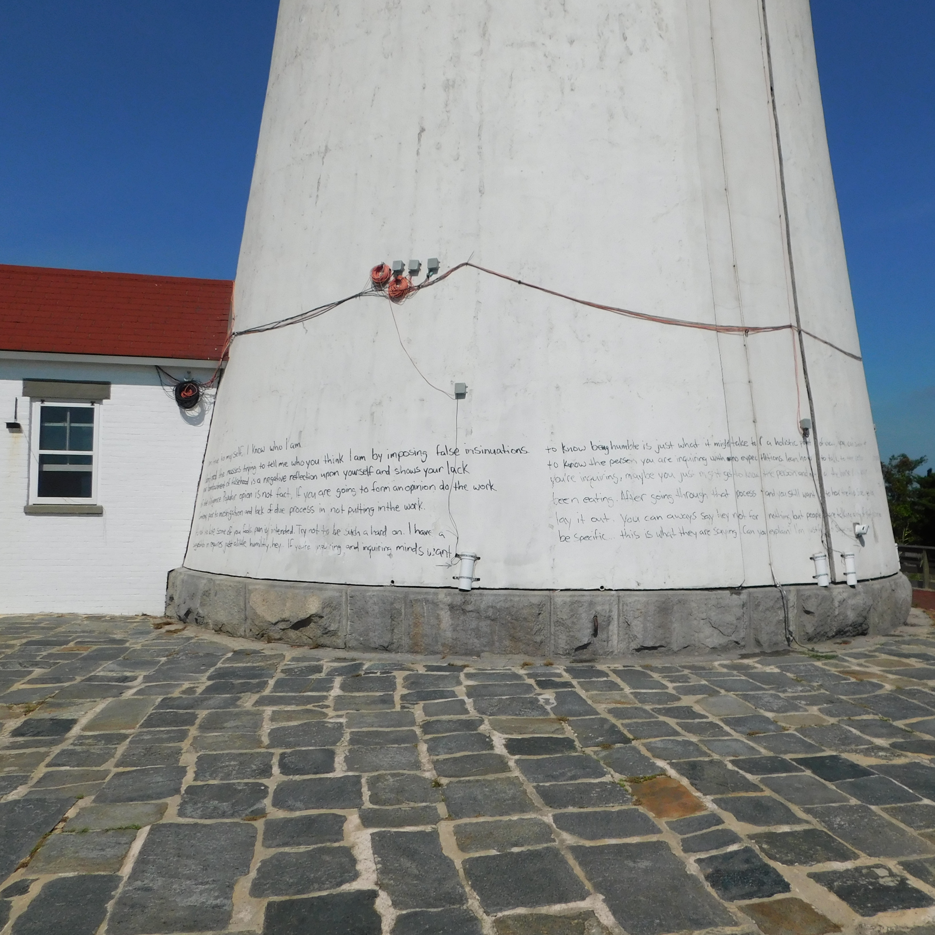 Graffiti vandalism in the form of black writing defaces the base of the historic Fire Island Lighthouse. NPS photo.