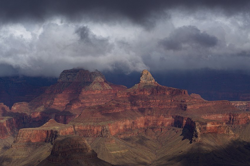 Dark storm clouds hang above inner canyon cliffs in Grand Canyon National Park.