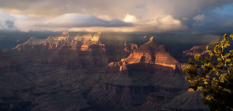 Sunlight shines through clouds above the Grand Canyon. NPS photo.