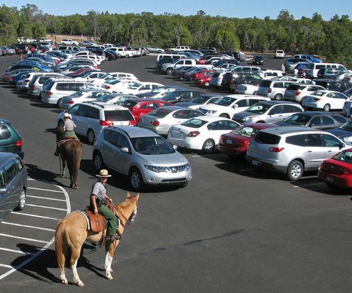 Two US Park Rangers conduct mounted horse patrol in a busy parking area in Grand Canyon National Park. NPS photo.