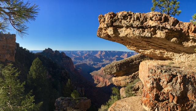 Large pieces of limestone jut out over a cliff with the Grand Canyon landscape visible in the distance. NPS photo.
