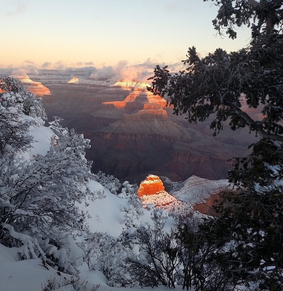 Snow brightens the rim of the Grand Canyon, and sunlight shines on O'Neil Butte in the inner canyon.