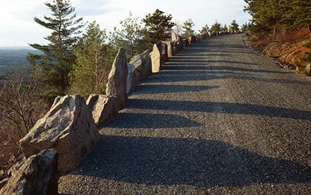 Jagged stones cast shadows on a road leading up the side of a hill in autumn