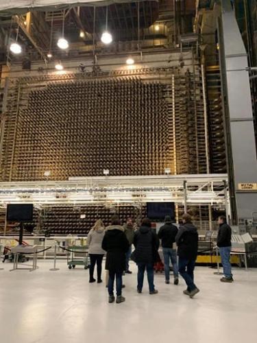 A group of people on a tour of a nuclear facility stand in front of the B Reactor.