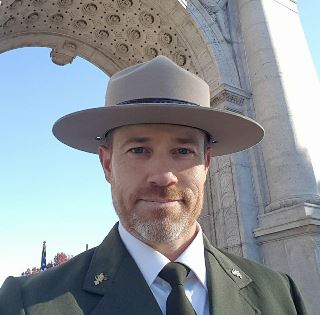 Steve Sims in front of granite arch memorial.