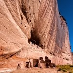 Masonry cliff dwellings in a high, red cliff.