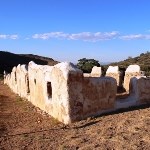 Earthen walls that look melted in front of a blue sky.