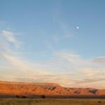 Far cliffs with a blue sky and moon far above.