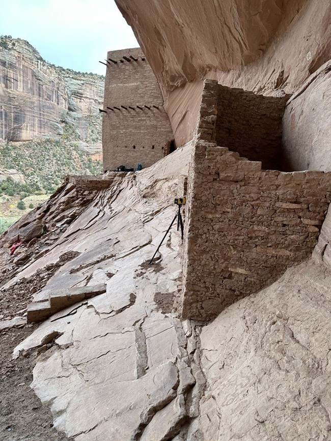 Looking out of the alcove to the sandstone walls with laser scanning equipment set up.