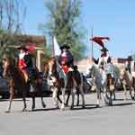 Men in uniform on horses in a parade.