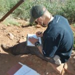 A man sitting filling out an archaeological form.