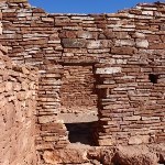 A doorway in dry-laid red-rock masonry.