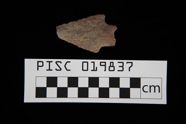 PISC_019837_20140916_111805 stone projectile point with checkered centimeter scale below on black background.