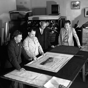 Black and White image with Thomas Vint. Thomas Vint and staff reviewing park master plans around a large table.
