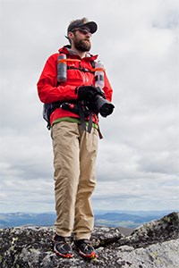 man in outdoor attire standing atop a mountain man in outdoor attire standing atop a mountain
