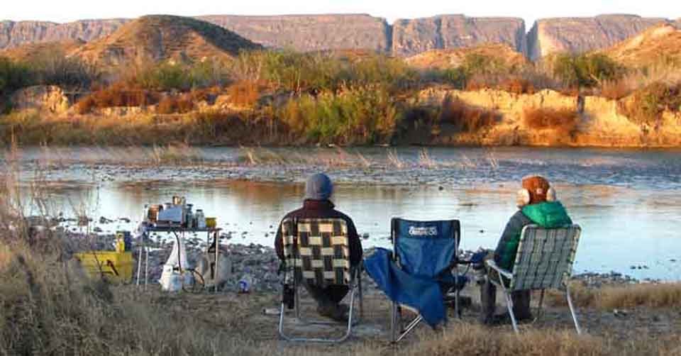 People sitting alongside the Rio Grande River in a peaceful setting. People sitting alongside the Rio Grande River in a peaceful setting.