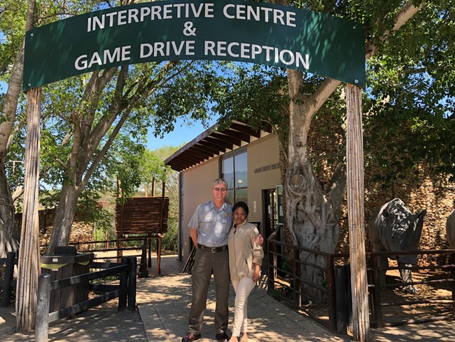The superintendent of Lake Roosevelt NRA stands outside Addo Elephant National Park Visitor Center with a park employee.