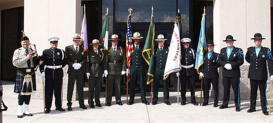 Eleven people in dress uniform stand in front of the Jack Wilson Building at the National Interagency Fire Center