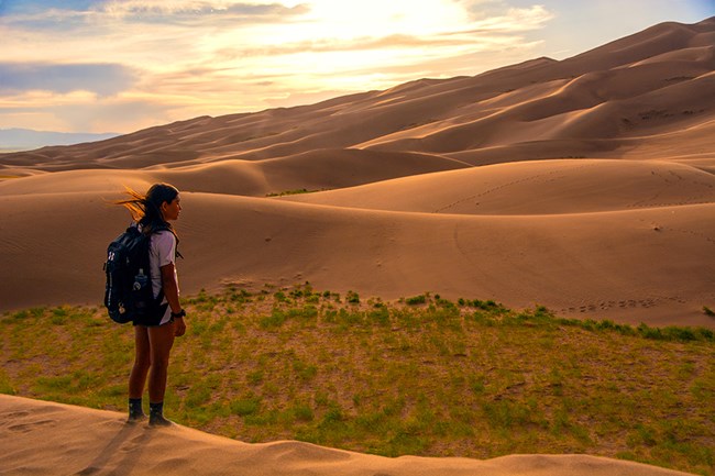 Visitor takes in the views on top of a sand dune.