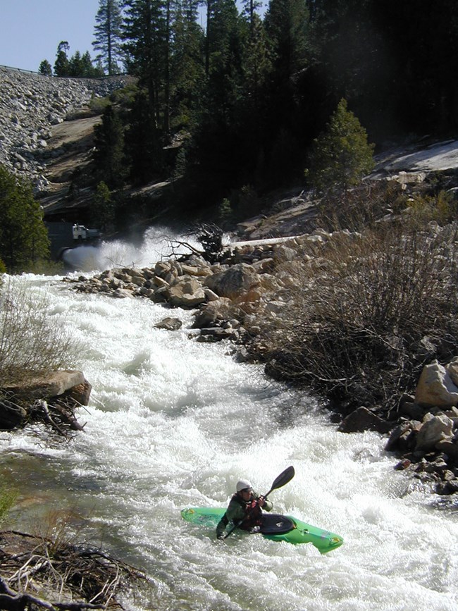 kayaker in green kayak descending a challenging rapid