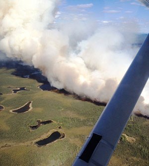 lt= Aerial view of smoke and flames blackening tundra.