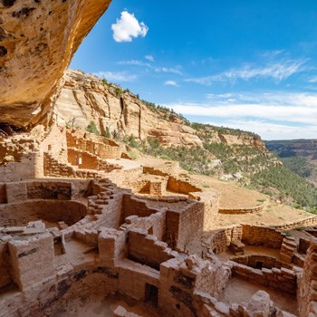 Mesa Verde National Park’s Long House Cliff Dwelling Kivas on a sunny day with the cliff shadowing the Native American ruins.