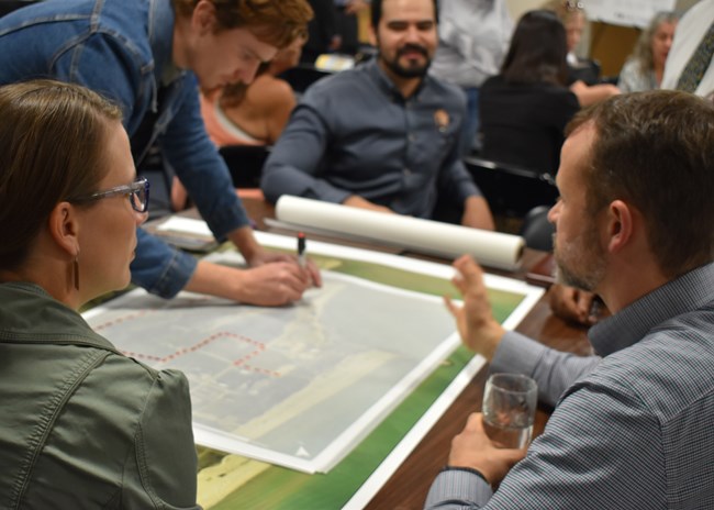 National Park Service staff and partners draw a potential trail on a map during a community meeting.