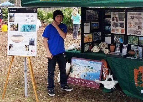 A student volunteer assists at a tabling booth at an event.