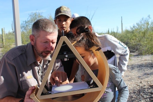 Park Ranger assists students view the sun through a solar scope