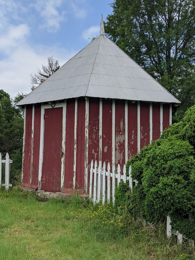 Red wooden building with white trim and tin roof.