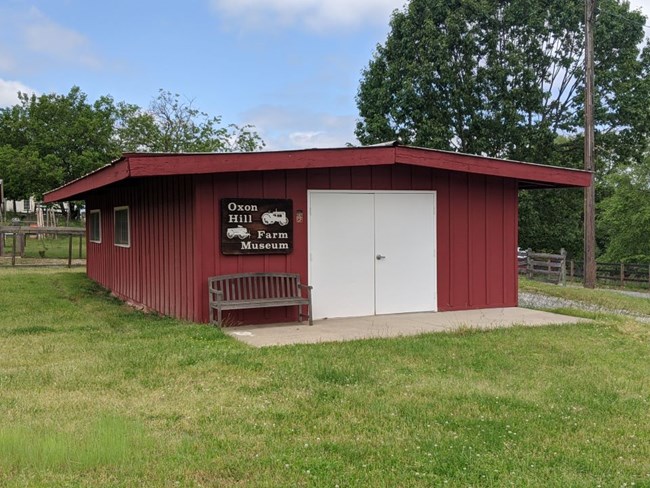 One story red wood building with a tin roof.