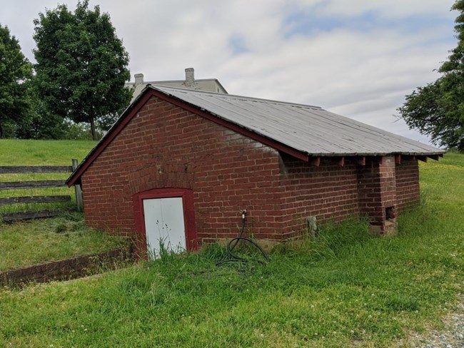 Brick building, partially underground with a ramp to the door.