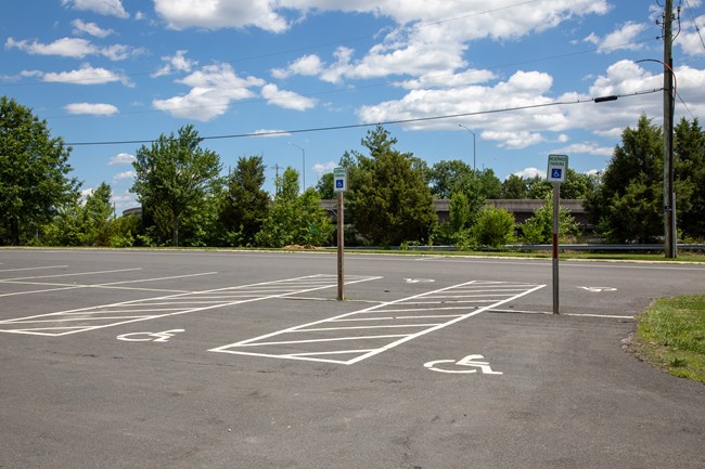 An asphalt parking lot with four spaces with access aisles reserved for visitors with disabilities.