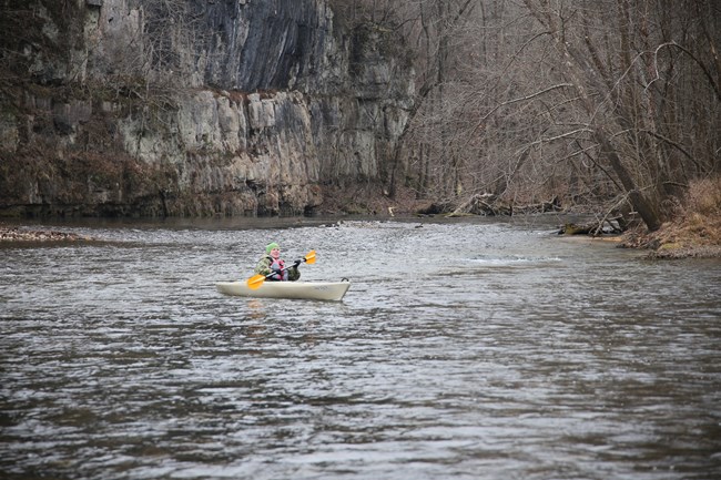 woman in kayak bundled up during winter float on river