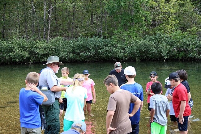 A National Park Ranger stands in the water with students during a water program