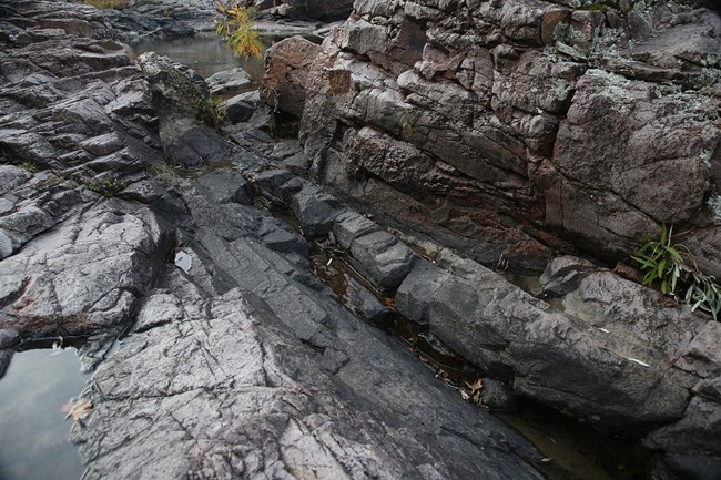 different hues of rhyolite from purple to almost black can be seen in this channel carved by water