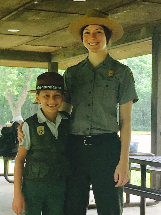 female Ranger stands with a recent Junior Ranger graduate