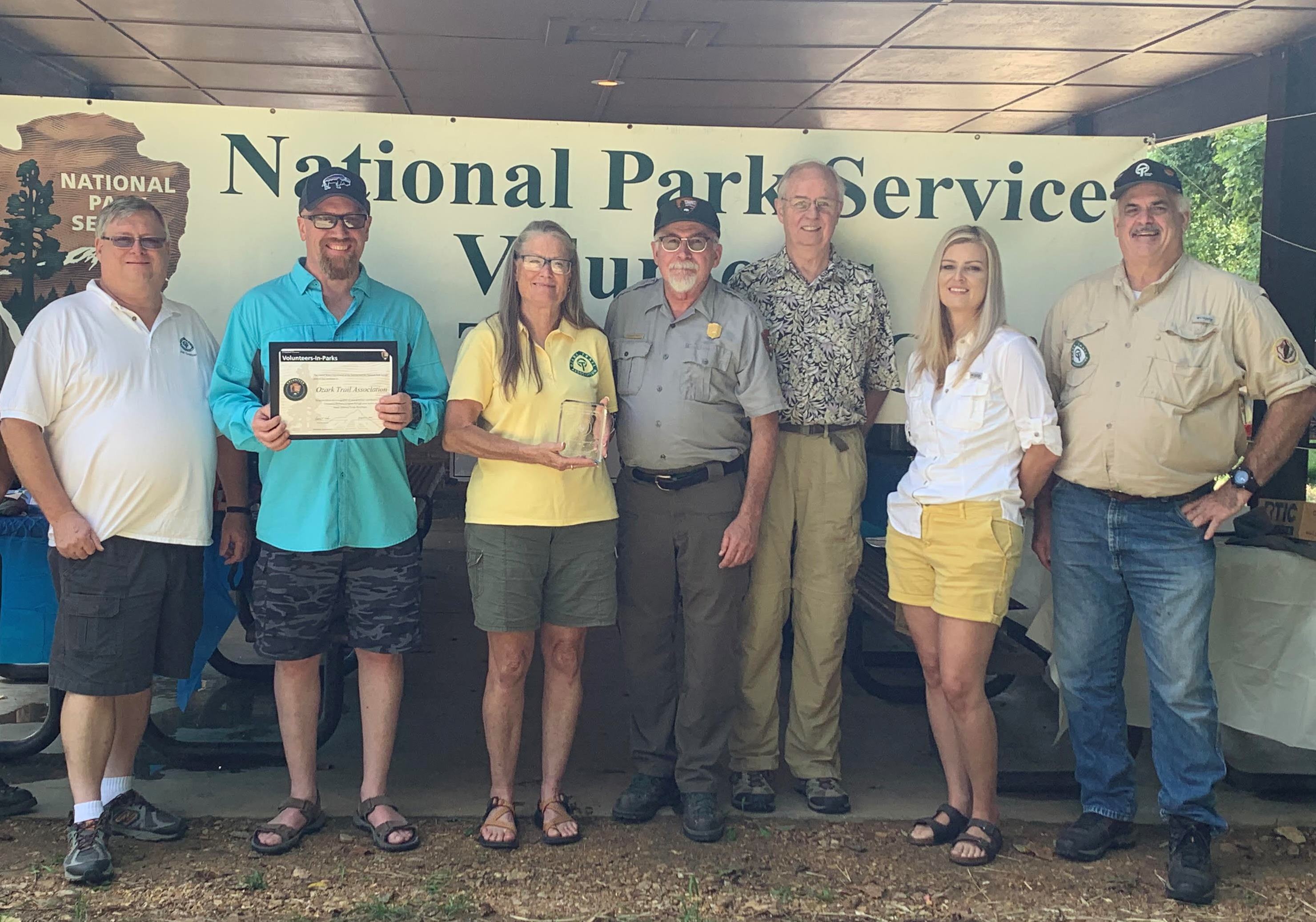 ozark trail association members holding award in front of volunteer banner