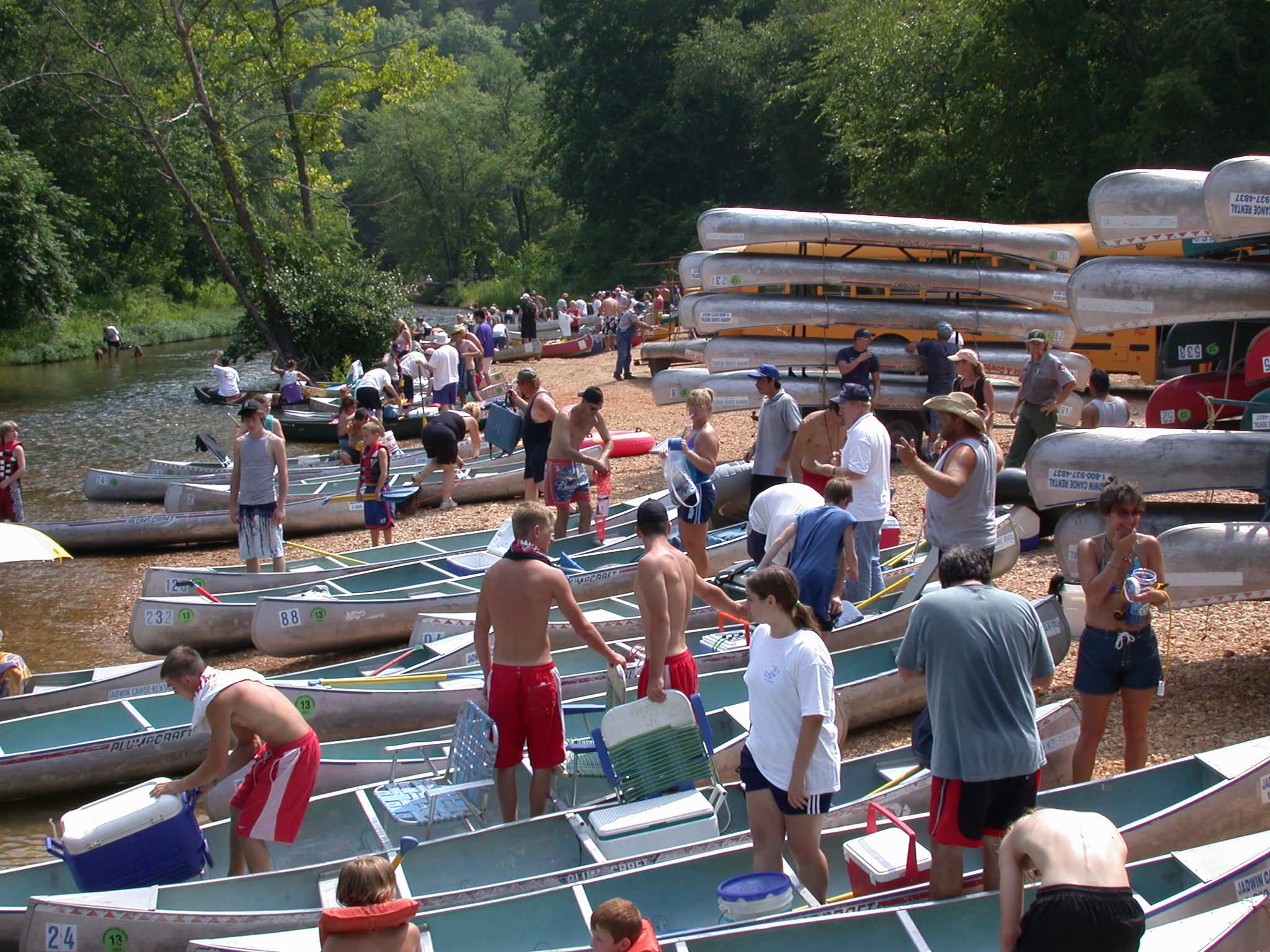 a crowded gravel bar with canoes and kayaks