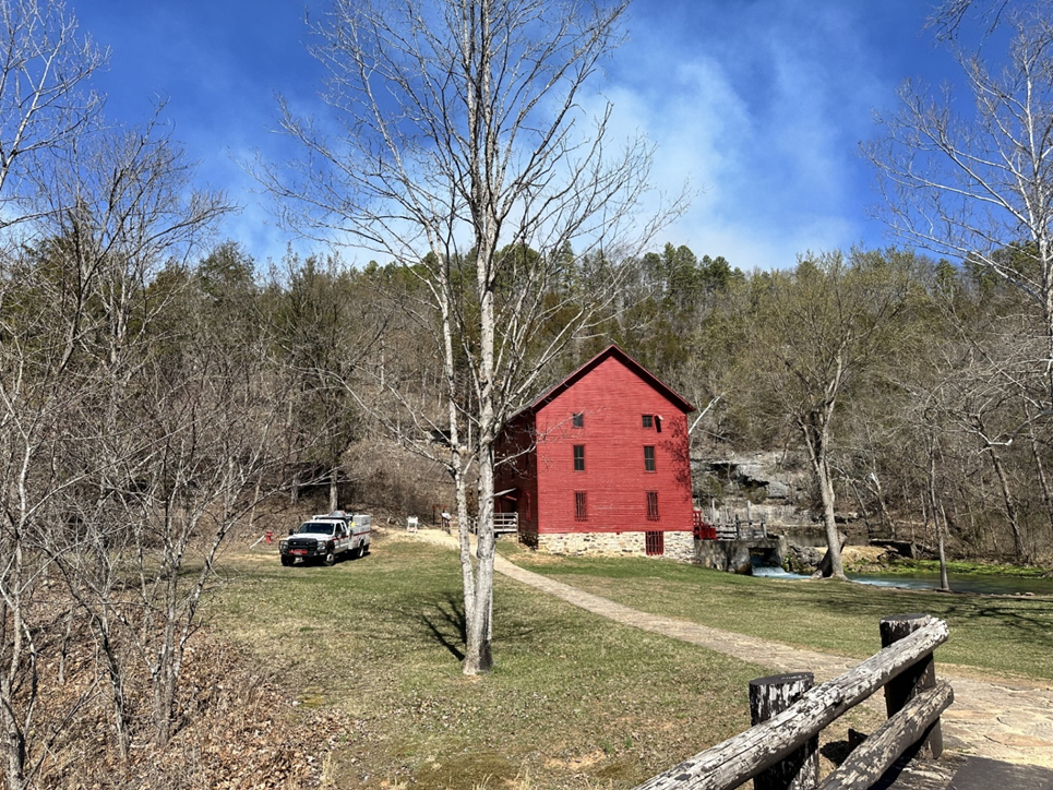 A fire truck is parked next to a large red mill.