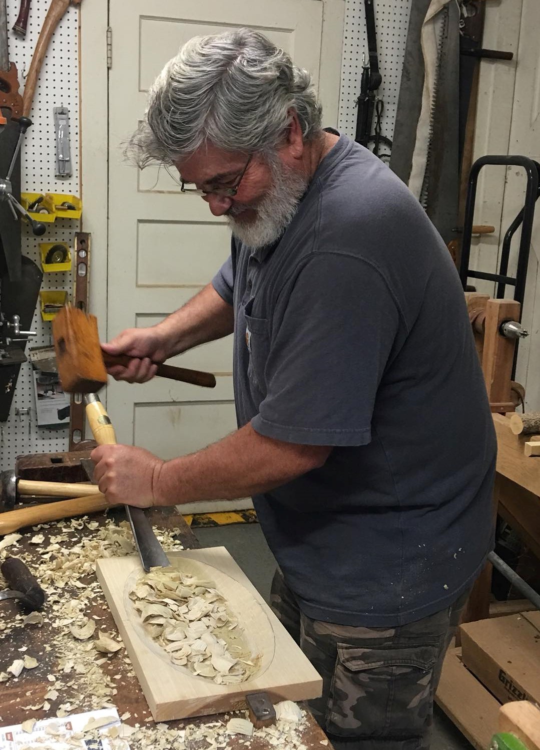 a man carves a bowl using hand tools in a shop